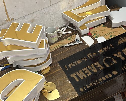 Gold-coloured 3D letters being assembled on the workbench at the ALFA Signage workshop in Sultanpur, India